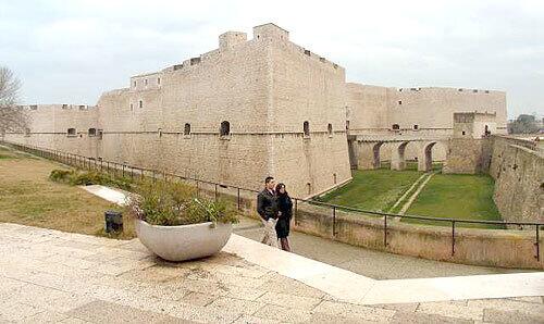 A couple explores Italy's Barletta Castello, constructed during the Norman period.