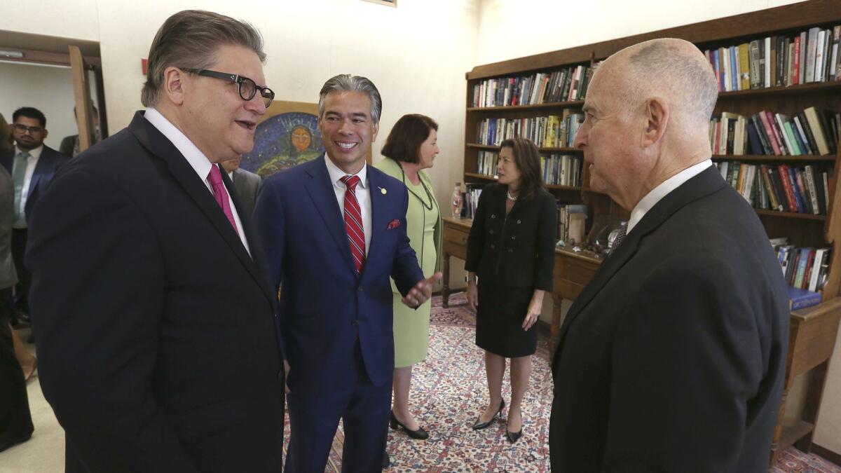 Gov. Jerry Brown, right, talks with state Sen. Bob Hertzberg (D-Van Nuys), left, and Assemblyman Rob Bonta (D-Alameda) in Sacramento before he signed their bill to end bail.