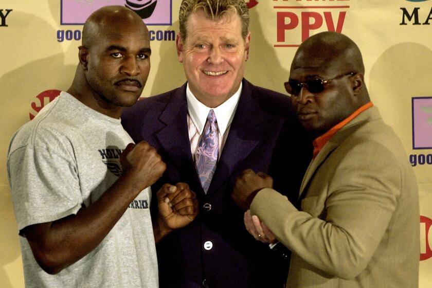 Dan Goossen stands between boxers Evander Holyfield, left, and James Toney in 2003.