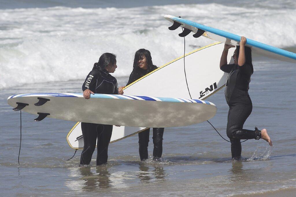 Girls from Save Our Youth’s Surf Days program laugh after trying to surf in west Newport on Thursday.
