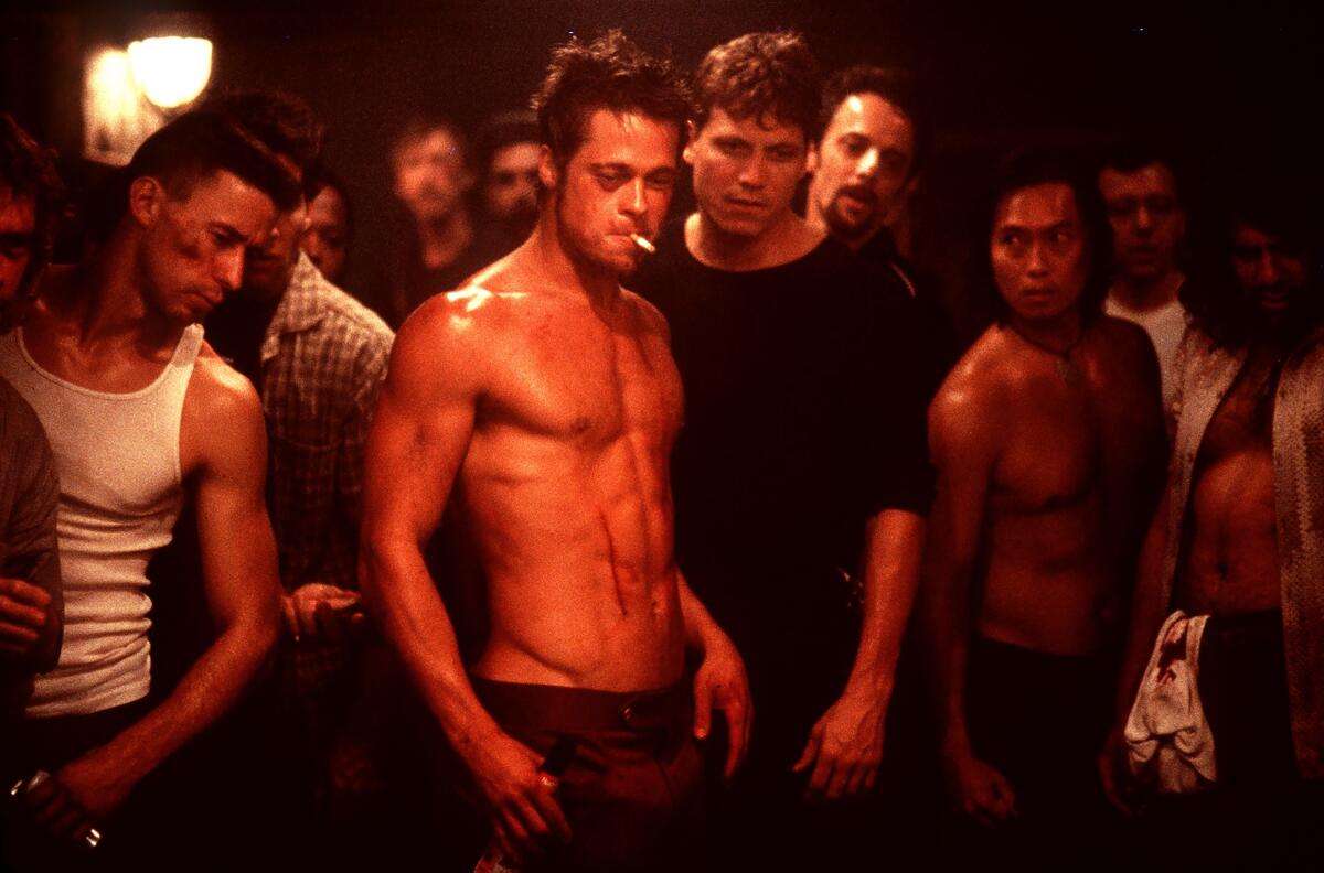 As Tyler Durden in 'Fight Club,' Brad Pitt stands shirtless with a cigarette perched in his mouth amid a group of men