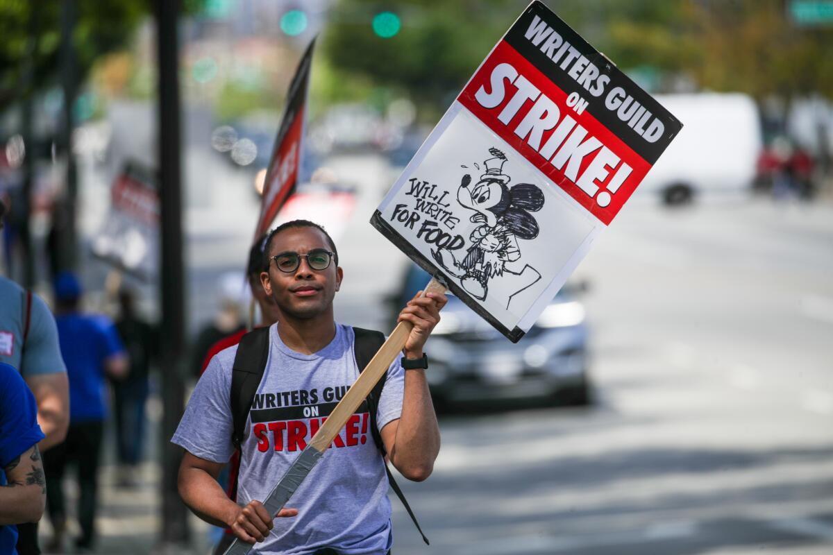 A Black person joins a Writers Guild of America strikers rally in Burbank.