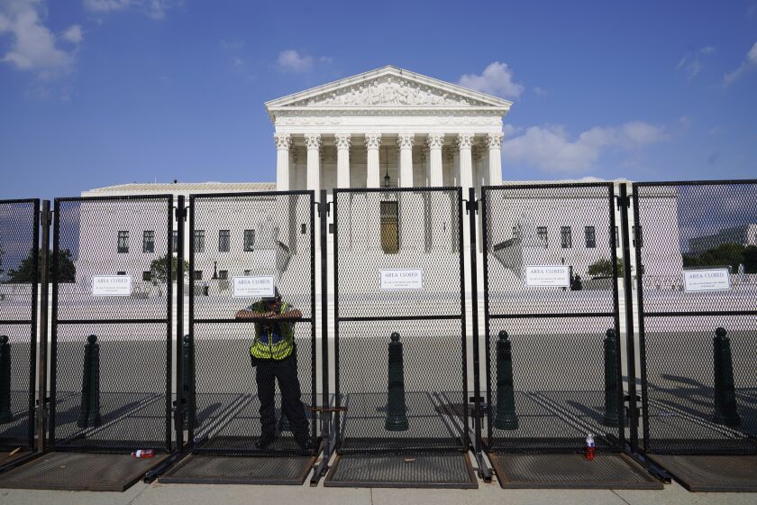 An officer rests on a fence outside the Supreme Court in Washington, Friday, June 24, 2022. The Supreme Court has ended constitutional protections for abortion that had been in place nearly 50 years, a decision by its conservative majority to overturn the court's landmark abortion cases.(AP Photo/Jacquelyn Martin)