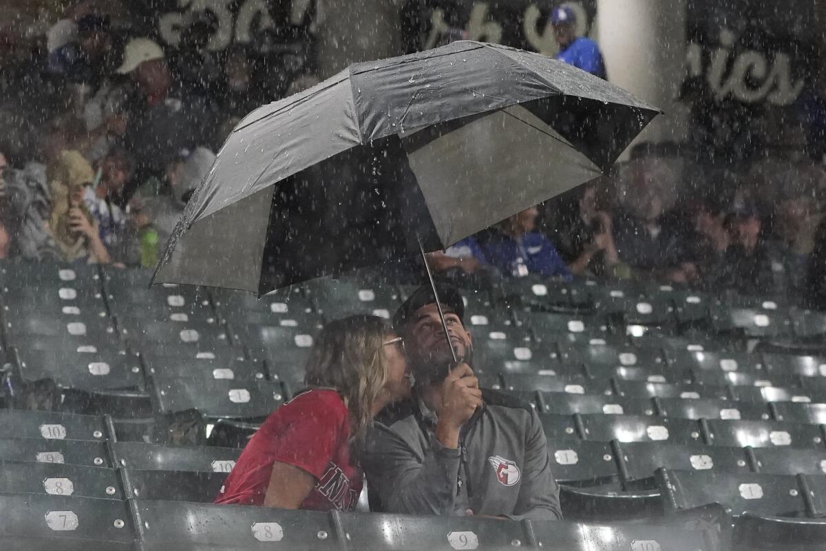 Two people sit under an umbrella in the stands.
