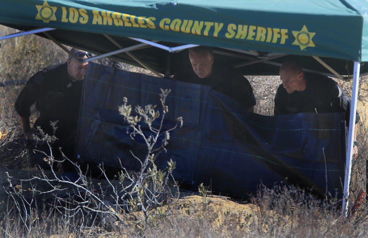 Investigators from the Los Angeles County Sheriff's Department study the scene off Lake Hughes Road in Castaic where a burnt body was discovered early Wednesday morning.