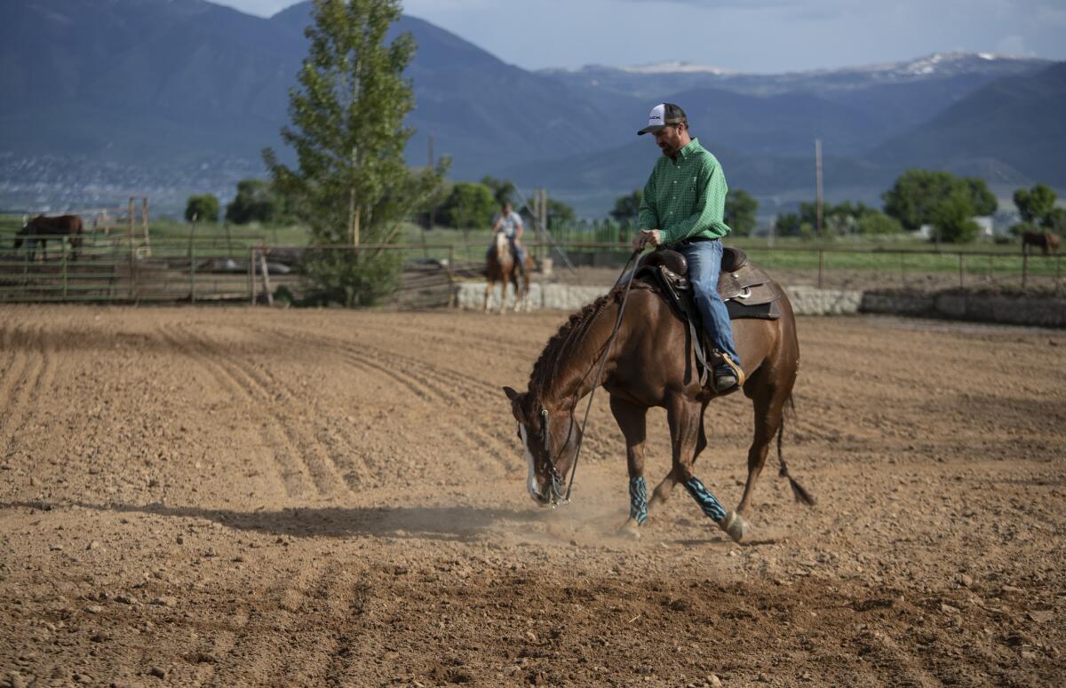 Nathan Ivie rides in an outdoor arena while giving lessons on his horse ranch in Benjamin, Utah. (Brian van der Brug / Los Angeles Times)