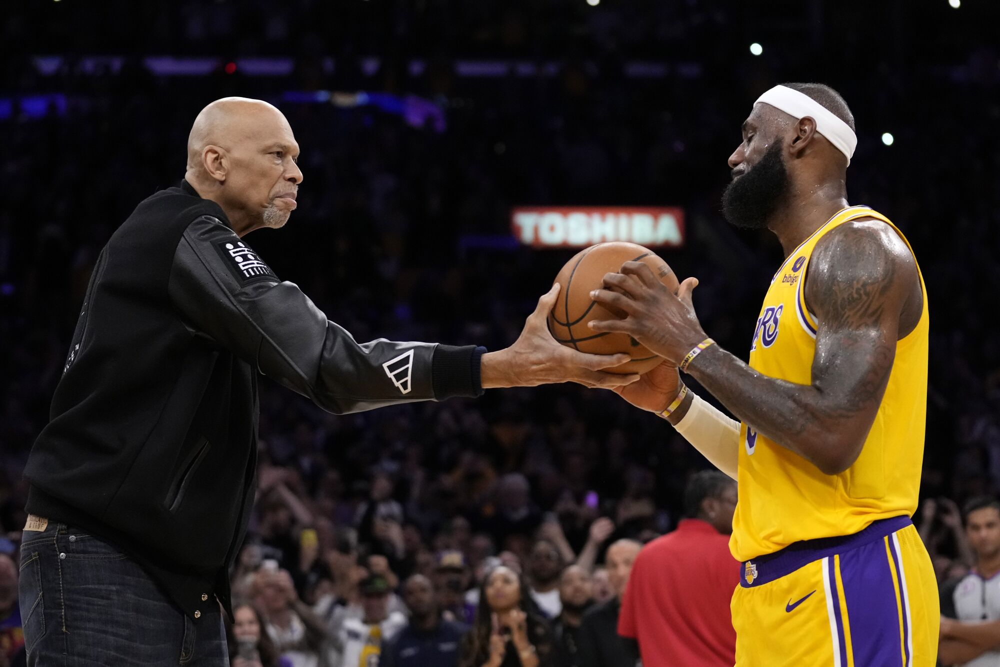 Kareem Abdul-Jabbar, left, hands the ball to Los Angeles Lakers forward LeBron James.