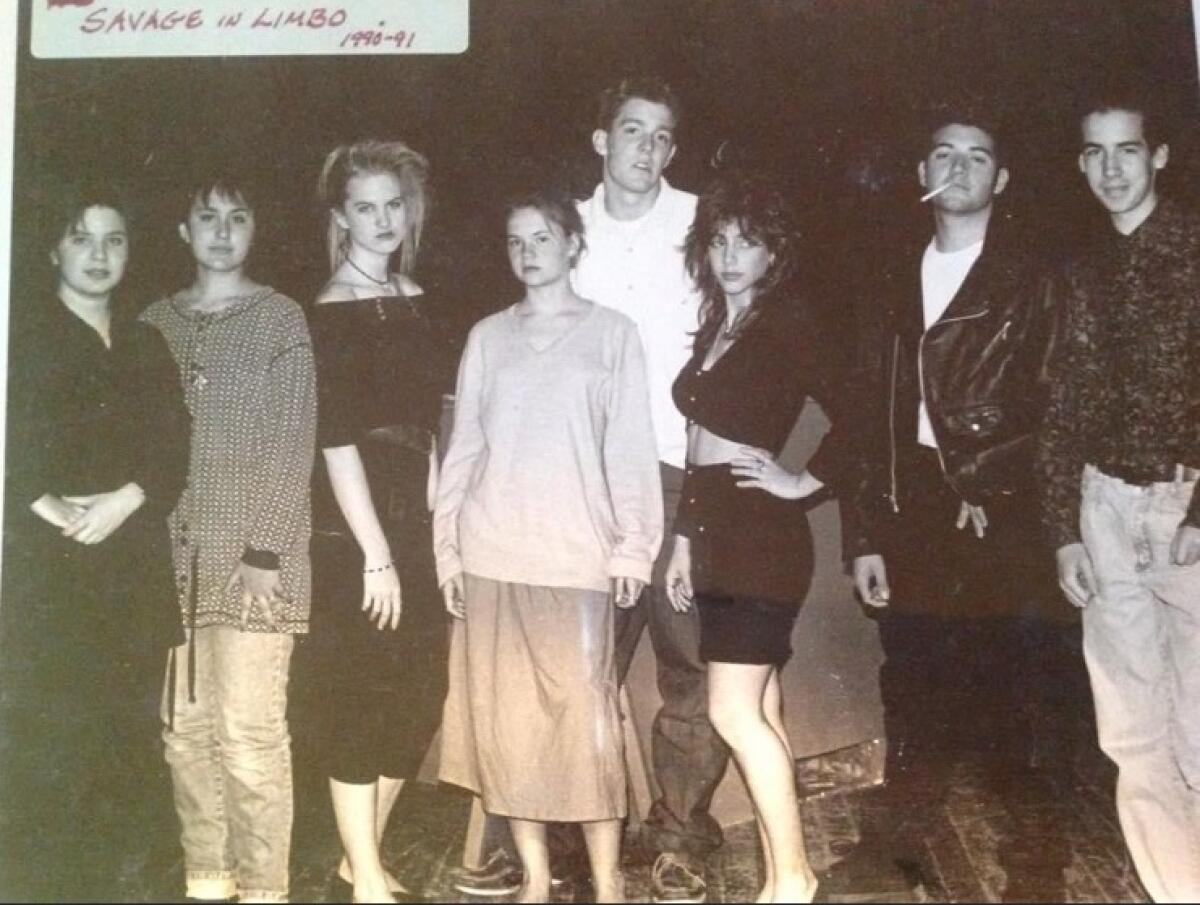 A group of teens pose together for a photo on a stage.