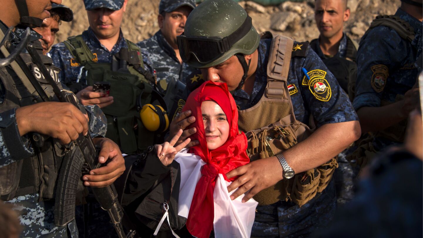 A girl joins members of Iraq's federal police in celebrating in the Old City of Mosul.