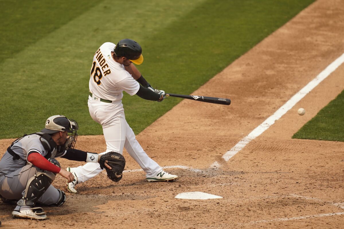 Oakland Athletics' Chad Pinder (18) hits a two-run single in front of Chicago White Sox catcher Yasmani Grandal during the fifth inning of Game 3 of an American League wild-card baseball series Thursday, Oct. 1, 2020, in Oakland, Calif. (AP Photo/Eric Risberg)