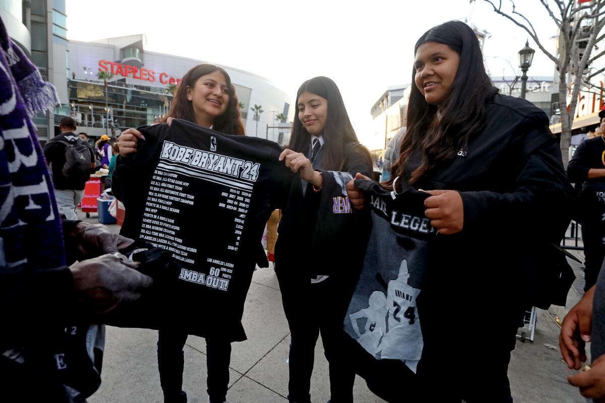 Bridgette Portillo, 13, from left; Martha Martinez, 14; and Elizabeth Hernandez, 12, hold Kobe Bryant memorial T-shirts from a vendor outside Staples Center.