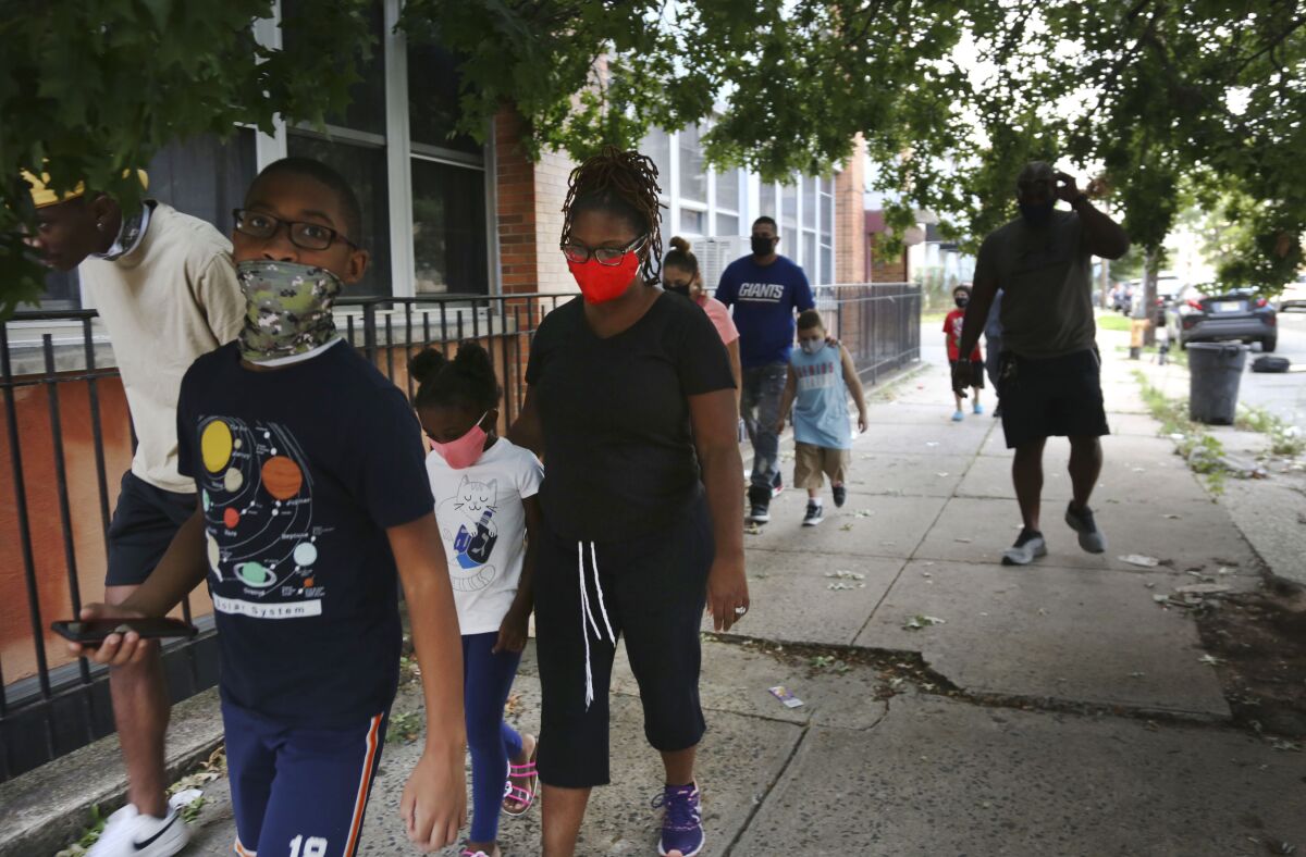 St. Francis Xavier School students and their families walk together in Newark, on Thursday, Aug. 6, 2020, after discussing the Catholic school's permanent closure announced the previous week by the Archdiocese of Newark. Nationwide, more than 140 Catholic schools will not reopen in the fall. (AP Photo/Jessie Wardarski)