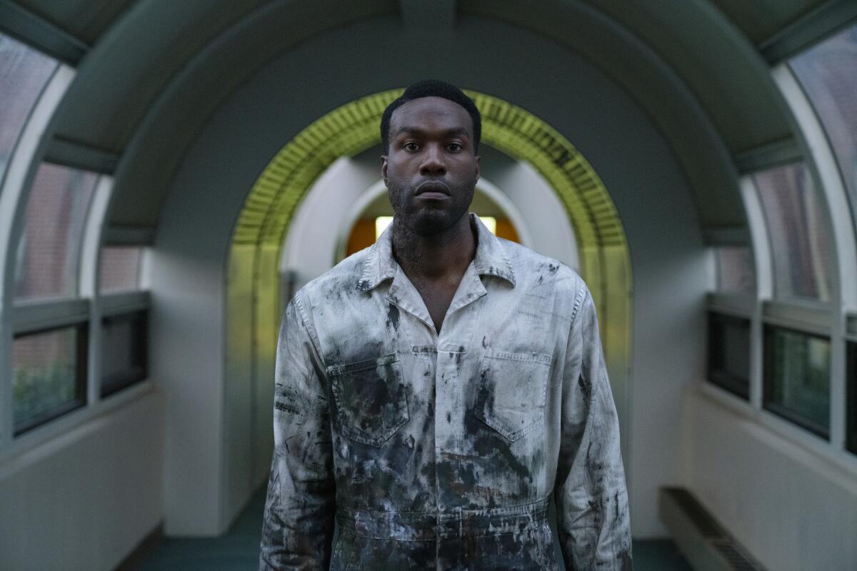 A man in a stained jumpsuit in a hallway
