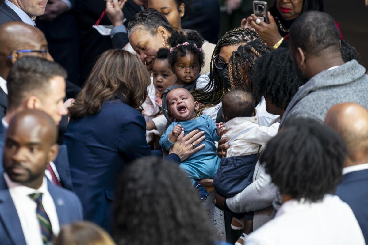 Vice President Kamala Harris greets a crying baby among a group of expecting families.