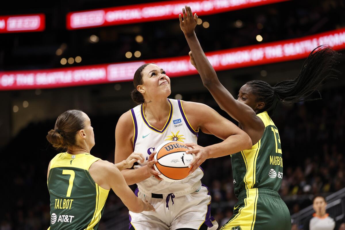 Sparks center Liz Cambage tries to power her way through the defense of Seattle's Stephanie Talbot and Ezi Magbegor.