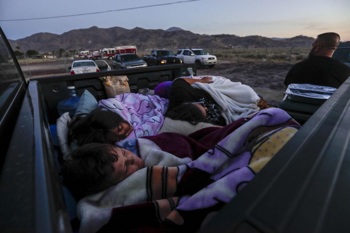 The Horta family sleeps in the back of their pickup truck in a fire station parking lot in Trona as the sun rises hours after being forced from their home by a magnitude 7.1 earthquake. (Robert Gauthier / Los Angeles Times)