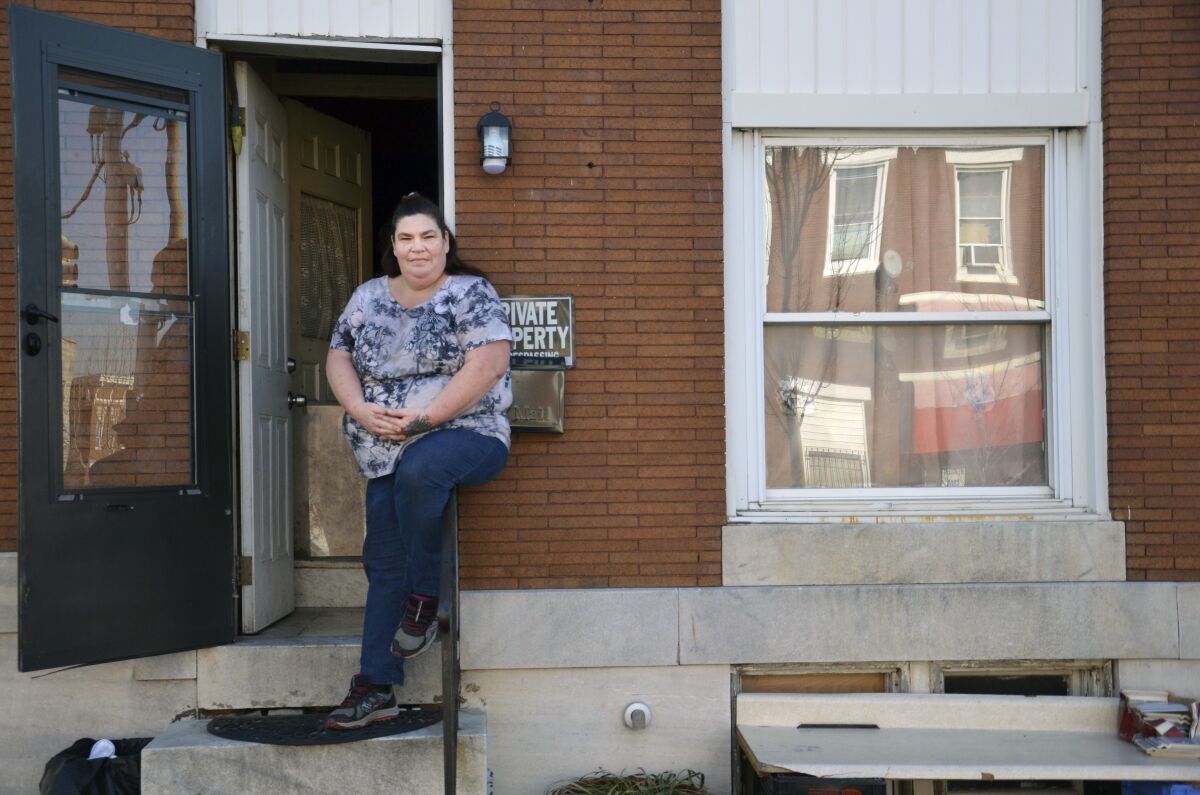 In this image provided by the Chronicle of Philanthropy, Elizabeth Vermillera sits on the front porch railing of her east Baltimore rowhouse. Vermillera's house was at risk of being seized by city officials for unpaid taxes totaling approximately $1,000. The Maryland Volunteer Lawyer Service helped Vermillera resolve the matter and keep her home. (Michael Theis/Chronicle of Philanthropy via AP)