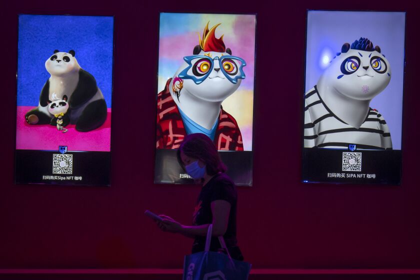 FILE - A visitor wearing a face mask walks past artwork displayed at an NFT (non-fungible token)-themed coffee shop at the China International Fair for Trade in Services (CIFTIS) in Beijing, Sept. 3, 2022. Fidelity Charitable, the nation's largest grant maker, is getting into NFTs, the digital images that are registered on the blockchain, despite a torrent of bad news from adjacent world of cryptocurrencies. (AP Photo/Mark Schiefelbein, File)