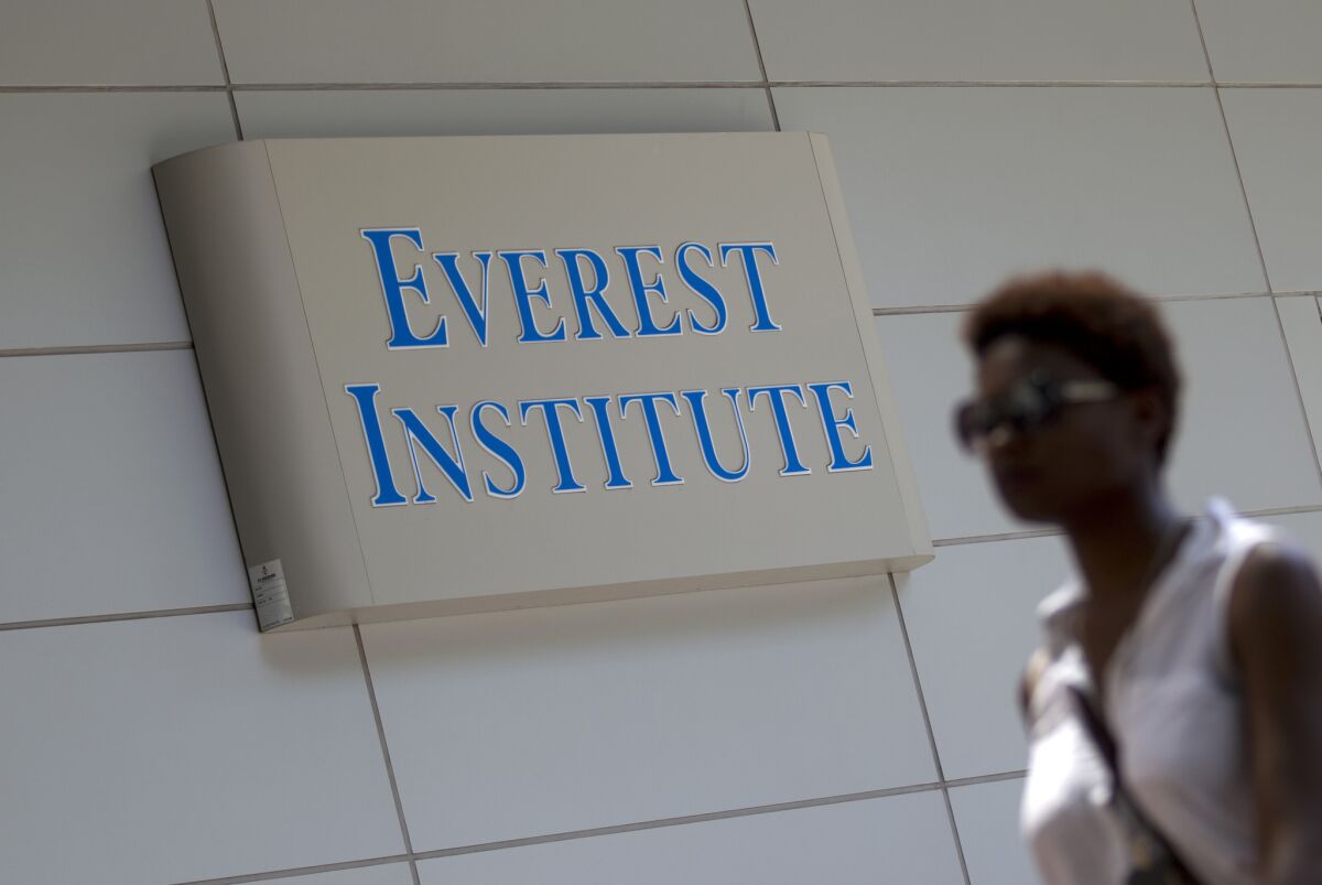 A person walks past an Everest Institute sign in Silver Spring, Md. Corinthian Colleges Inc., which owns Everest, announced Sunday it would cease all operations and shut down more than two dozen remaining schools.