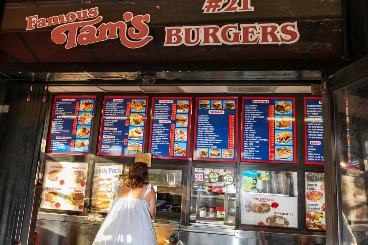 A burger stand customer facing the counter and menus