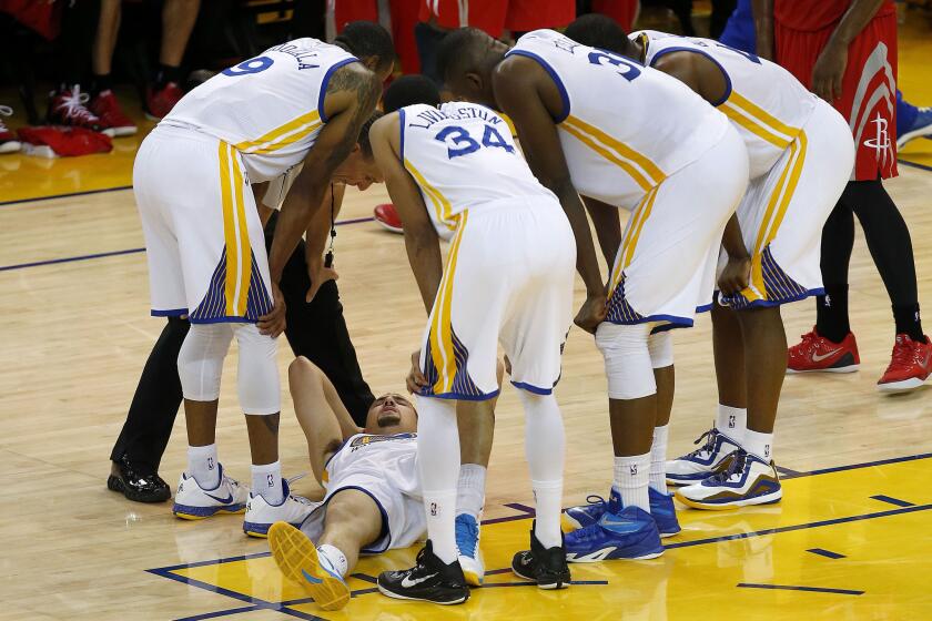 Klay Thompson is surrounded by his Golden State Warriors teammates after being hit in the head by a knee during a Western Conference finals game against the Houston Rockets.