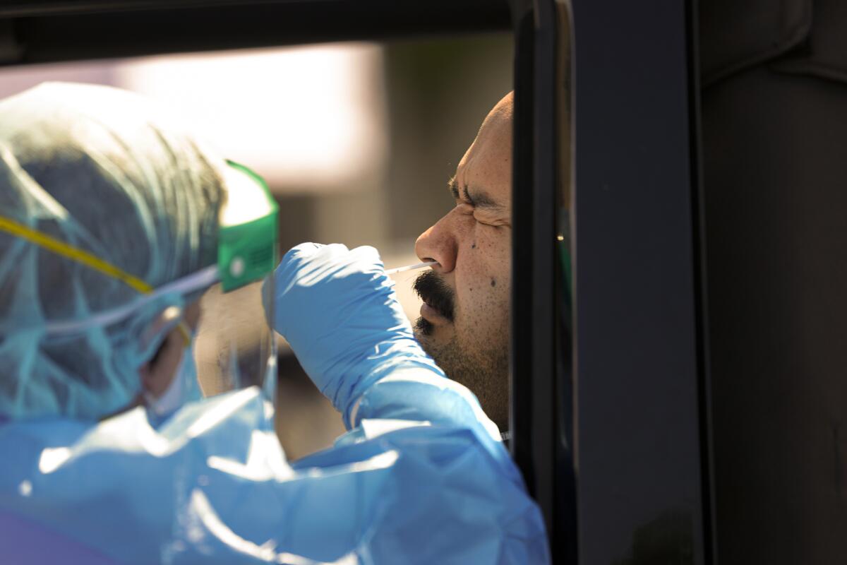 A healthcare worker collects a nasal swab from Victor Guardavo for coronavirus testing in San Bernardino County.