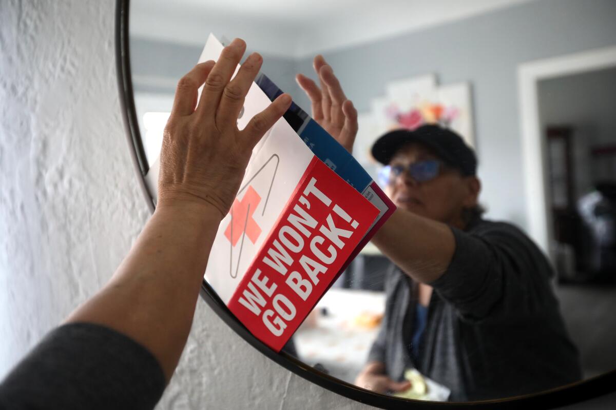A woman puts up an abortion rights sign on a mirror in her home.