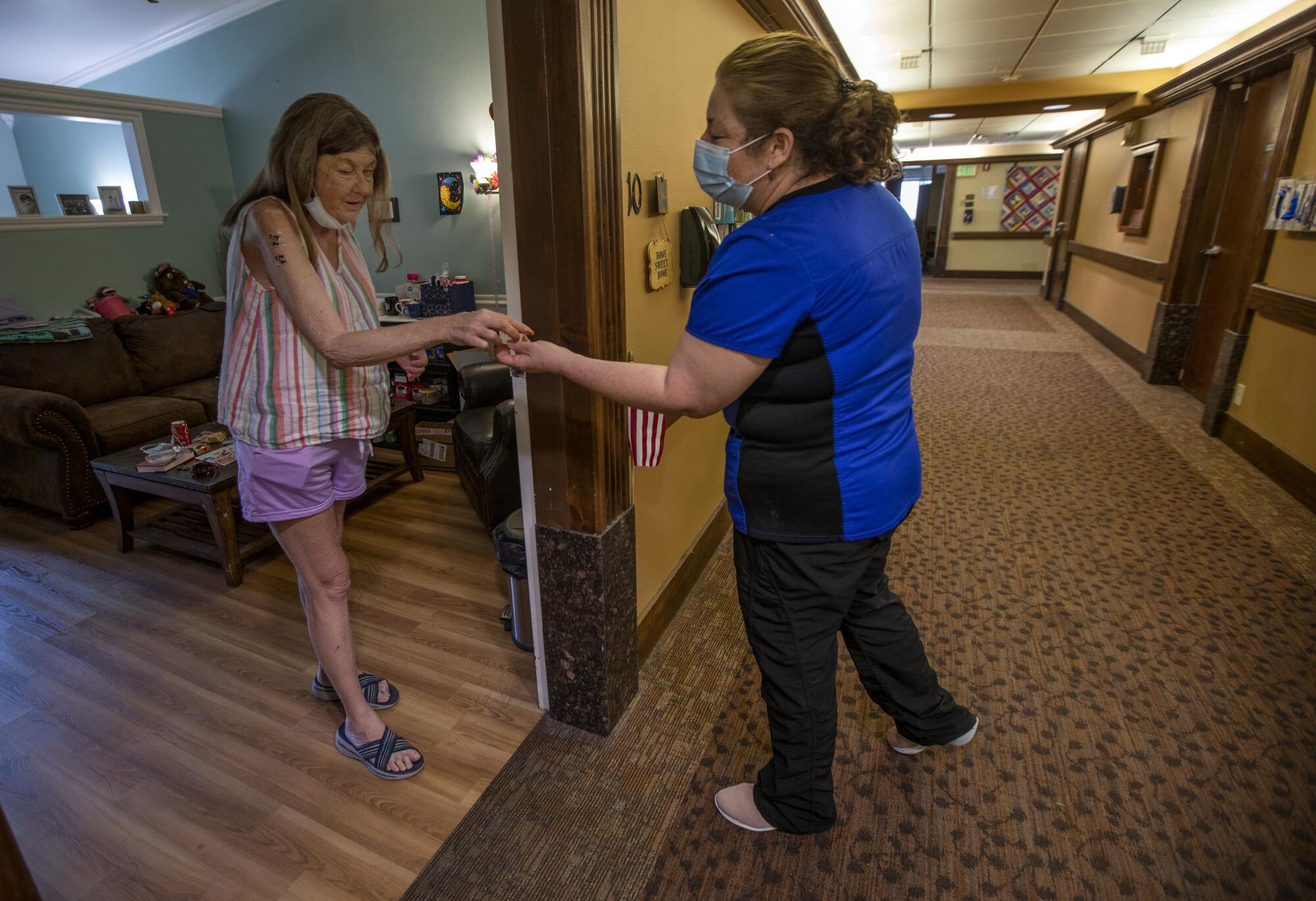 Rosalba Aguilera, right, hands medication to Patti Larsen, left, at the Inn Between in Salt Lake City.