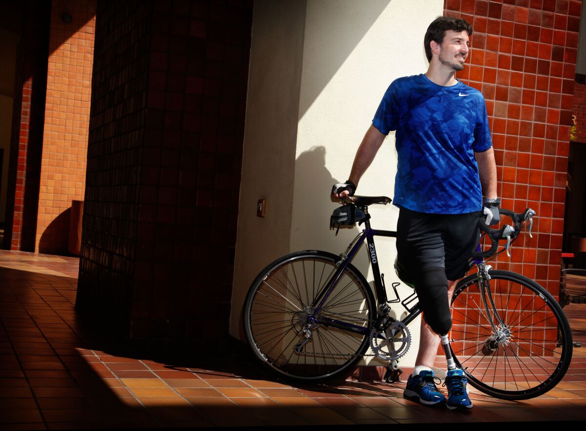 A man with one prosthetic leg stands next to his bicycle