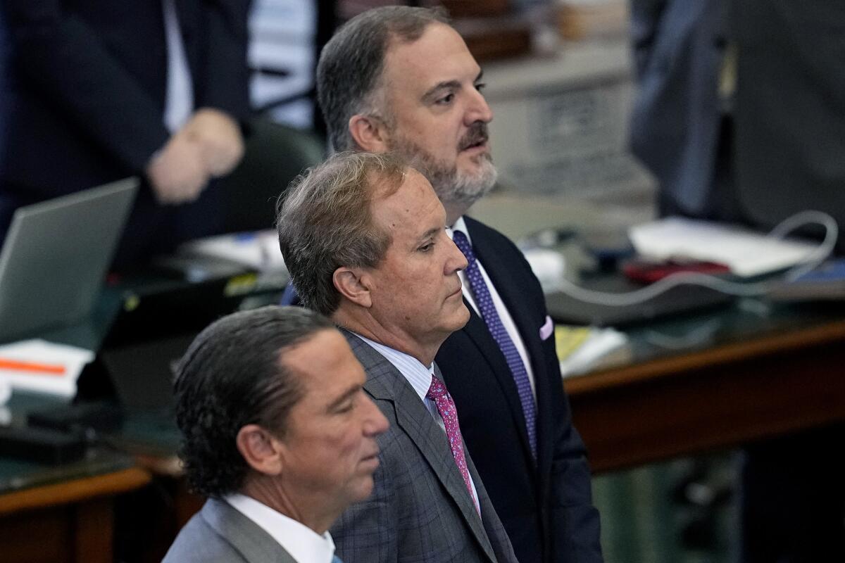 Suspended Texas state Atty. Gen. Ken Paxton stands with his attorneys flanking him