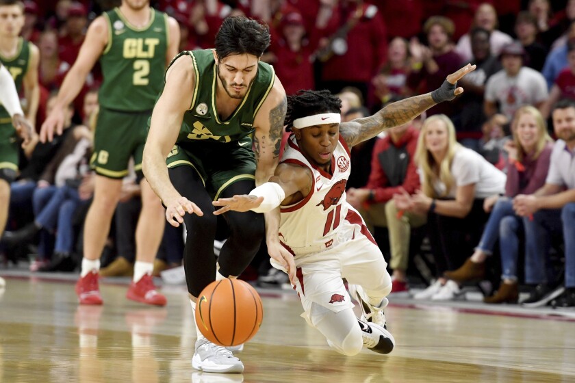 Arkansas guard Chris Lykes (11) knocks the ball away from Charlotte guard Luka Vasic (35) during the first half of an NCAA college basketball game Tuesday, Dec. 7, 2021, in Fayetteville, Ark. (AP Photo/Michael Woods)