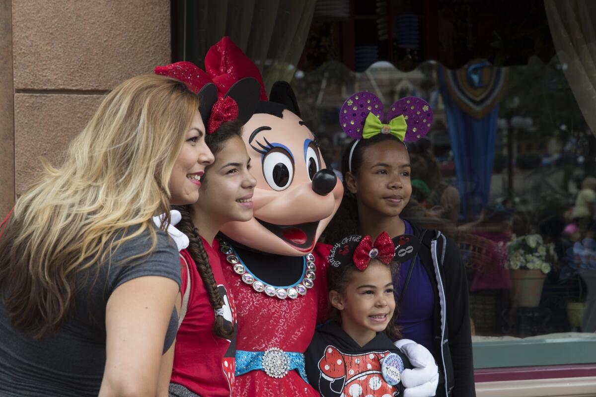 Minnie Mouse pauses for a photo with fans at Disneyland in Anaheim, Calif.
