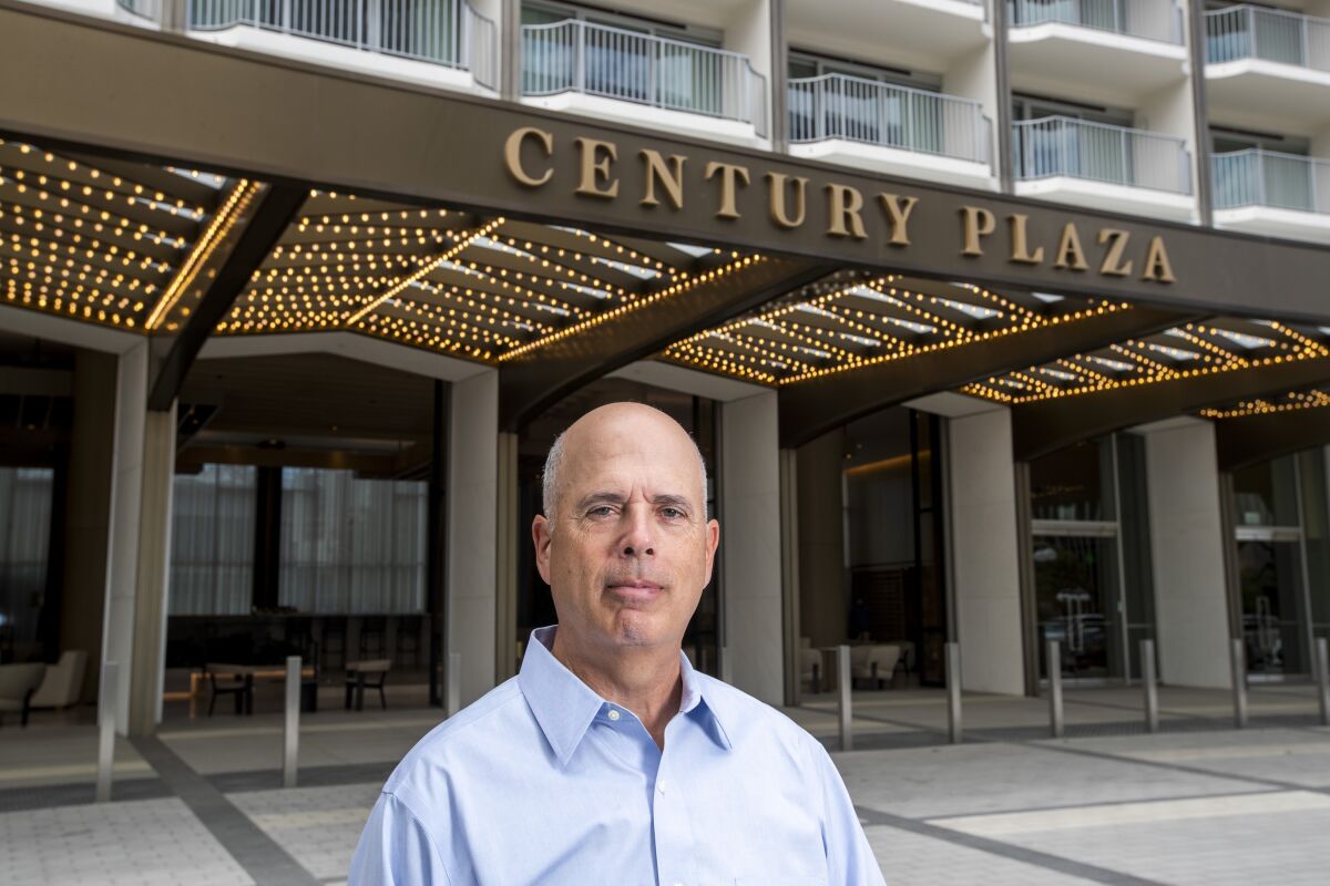 A man stands in front of a building with a marquee that reads "Century Plaza."