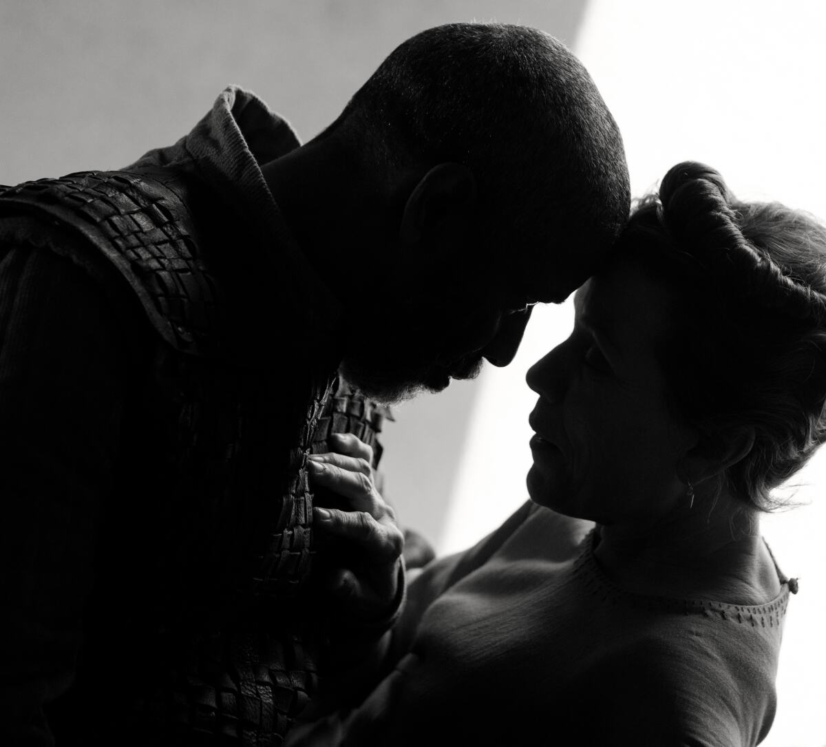 A man and a woman stand, foreheads together, in a black-and-white movie still.