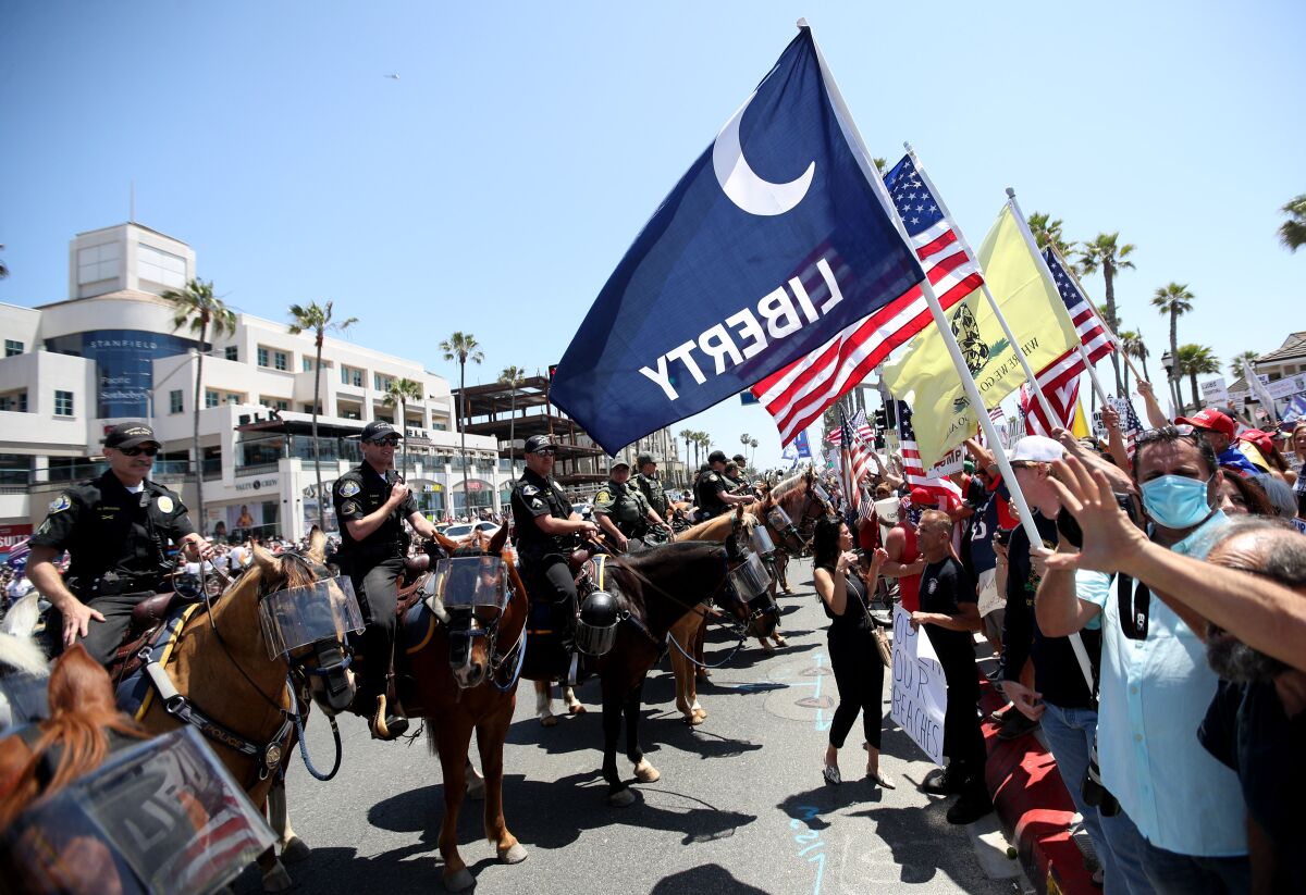 Police officers on horseback keep people away from the street during the protest at Main Street and Pacific Coast Highway in Huntington Beach on Friday.