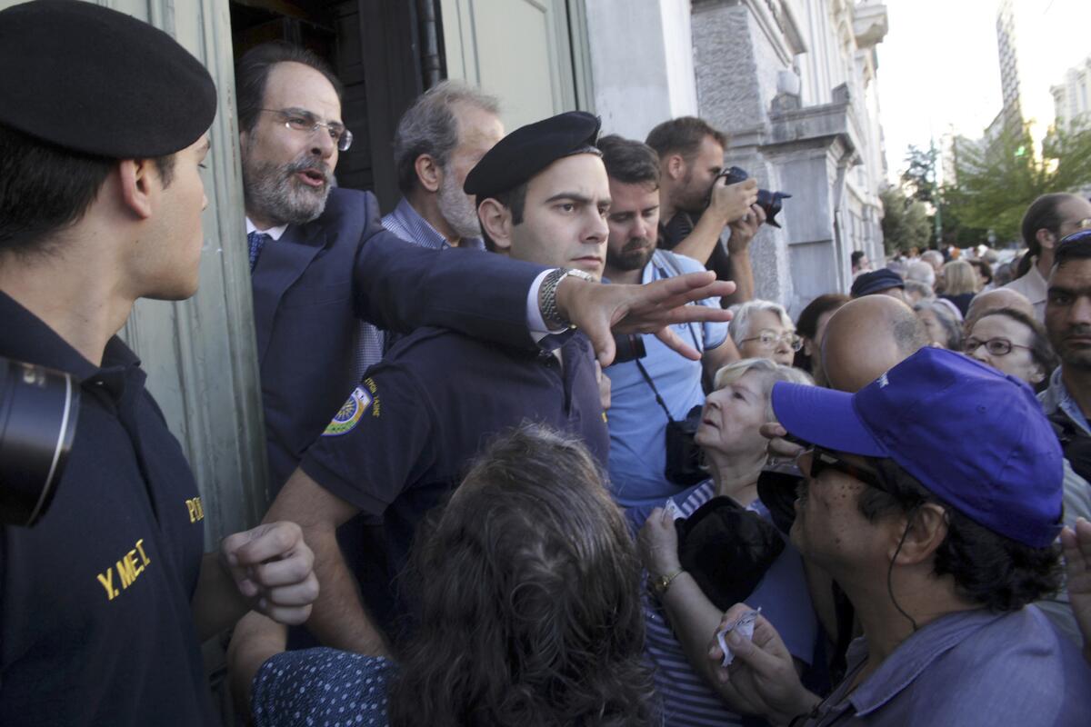 El gerente de una sucursal del Banco Nacional de Grecia pide a los pensionados que conserven la calma mientras esperan para entrar al edificio en Atenas, miércoles 1 de julio de 2015. Los pensionados son las víctimas olvidadas de la crisis griega. Sus pensiones fueron reducidas en los últimos años y puesto que muchos no tienen tarjetas bancarias, no tuvieron acceso a su dinero hasta que se dispuso una reapertura especial de los bancos para atenderlos. (AP FFoto/Spyros Tsakiris)