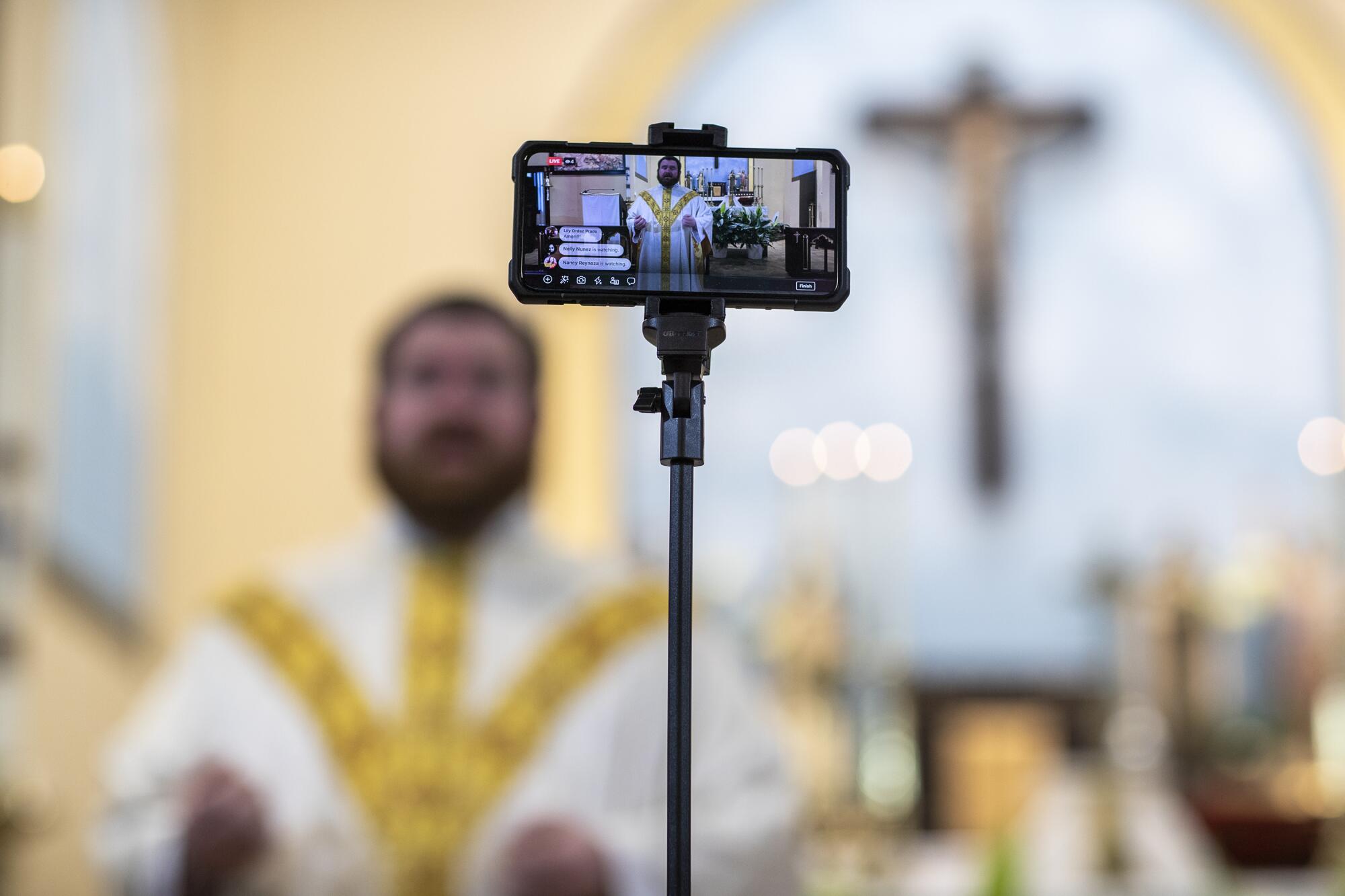 The Rev. Kristopher Cowles uses a phone to broadcast a homily from Our Lady of Guadalupe in Sioux Falls.