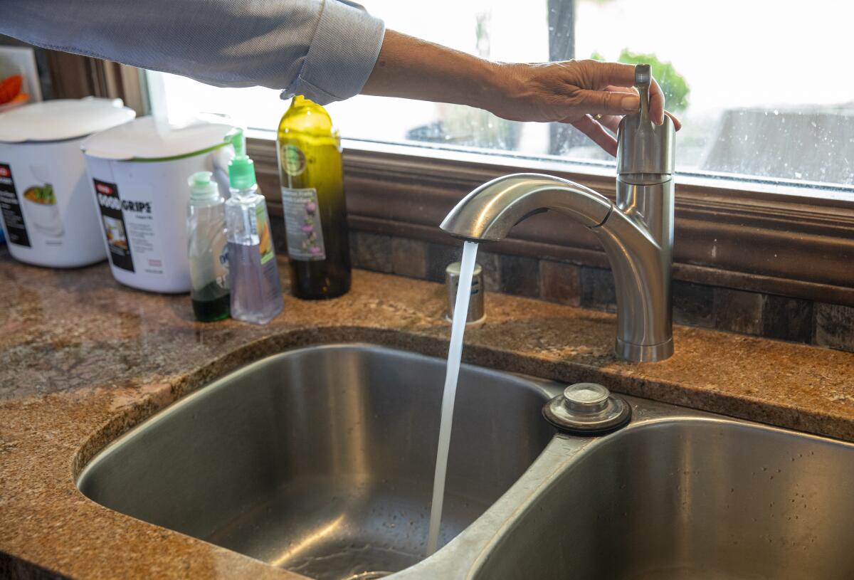 A person turns on a faucet at a sink.