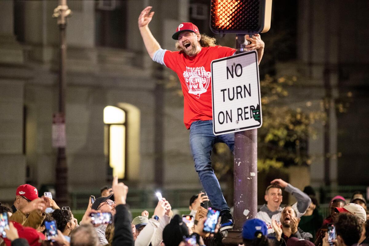 A fan celebrates on a light pole near City Hall after the Philadelphia Phillies advanced to the World Series on Oct. 23.