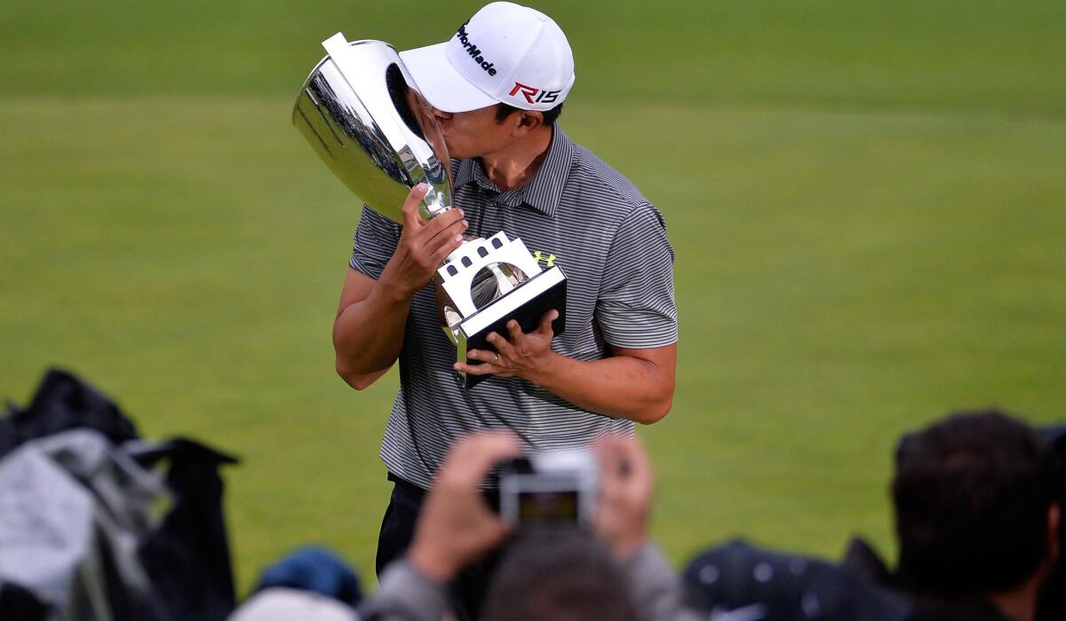 James Hahn gives the winner's trophy a kiss as he poses for photos after earning a playoff victory in the Northern Trust Open on Sunday at Riviera Country Club.