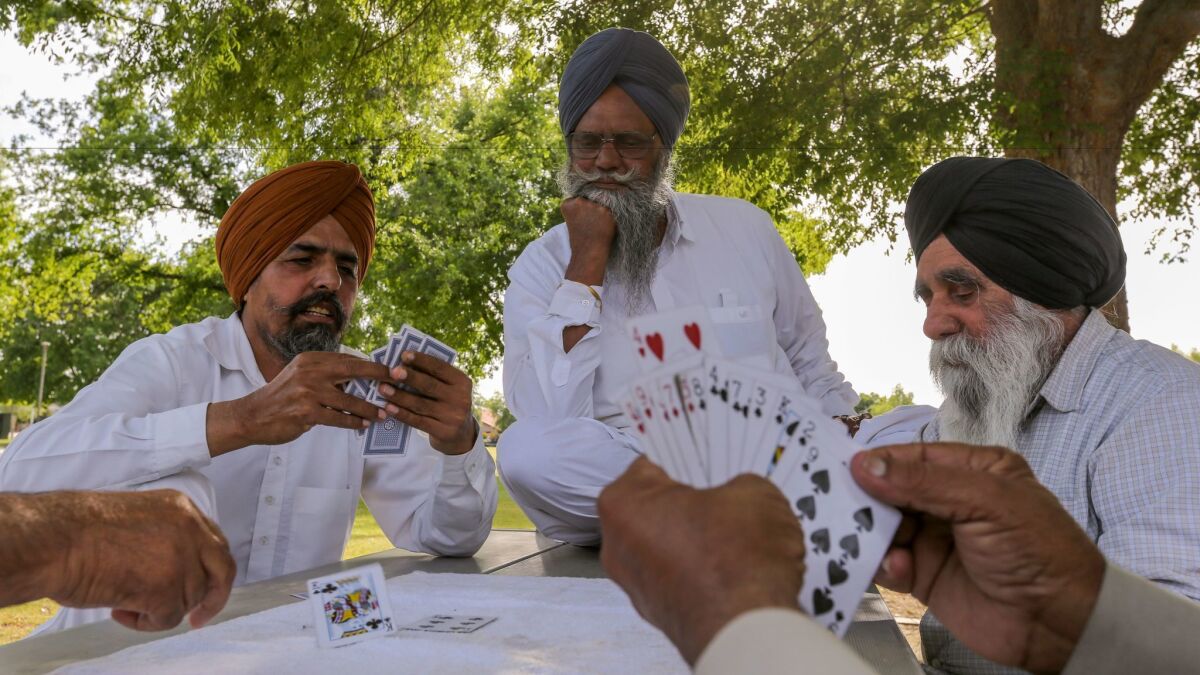 Sikh men play a card game in a neighborhood park in Bakersfield. (Irfan Khan / Los Angeles Times)