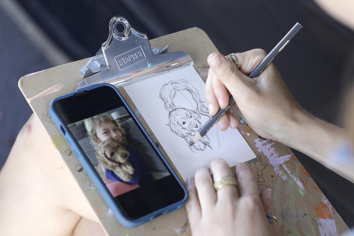 Isabella Weaver of Encinitas' House of Art pencil-draws a five-minute portrait of Zoey Miller and her dog,at LeucadiART Walk.