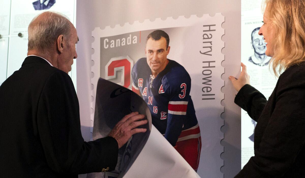Harry Howell, a former New York Rangers defenseman, and Lisa Raitt, Canadian minister of Transport, unveil a poster of a stamp dedicated to players from the Original Six teams in the NHL.