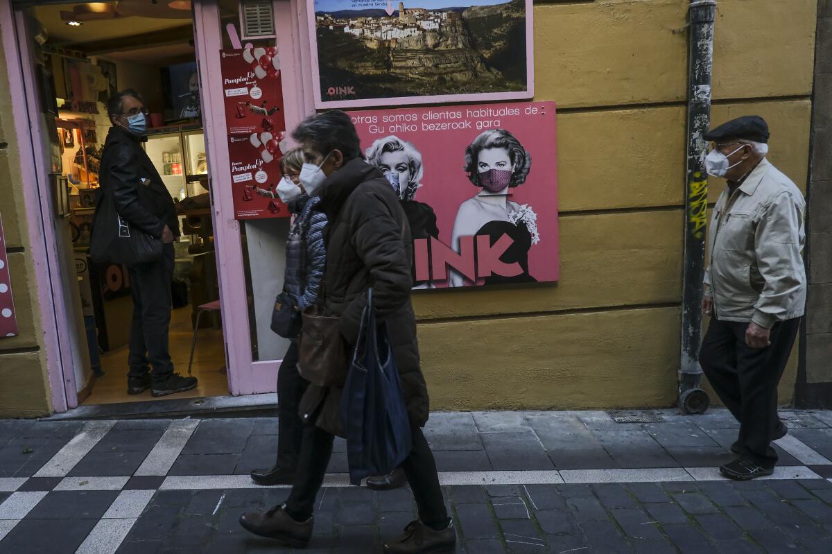 Unas personas con cubrebocas debido al coronavirus caminan por una calle en Pamplona, norte de España.