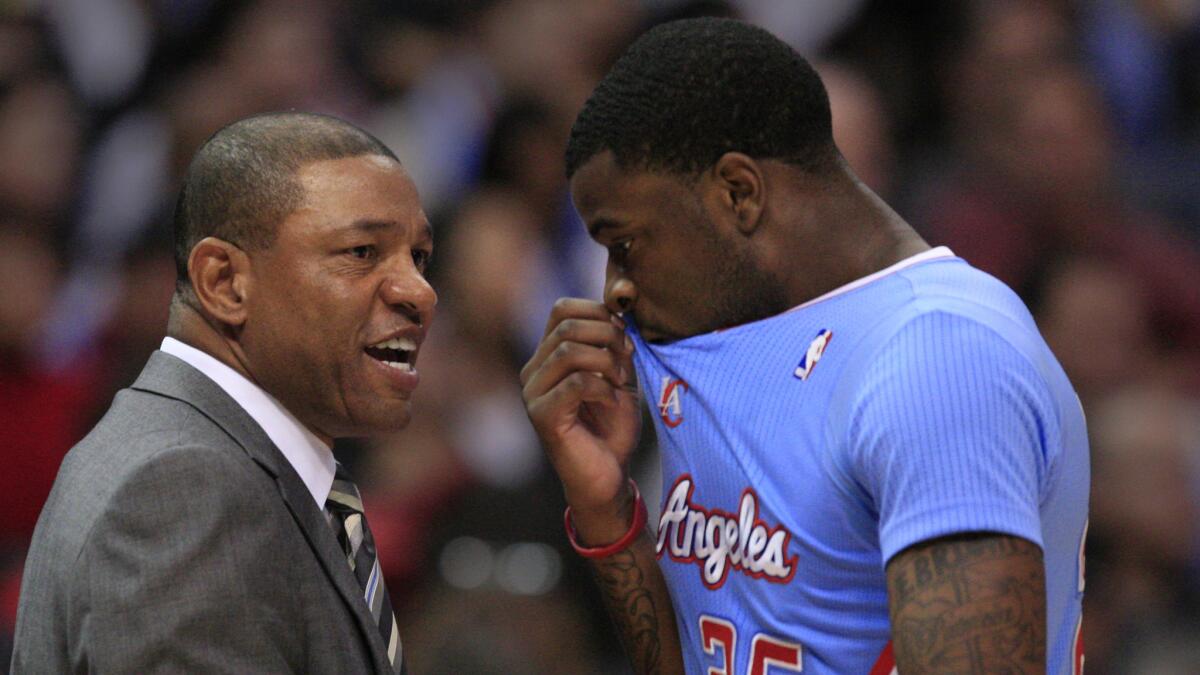 Clippers Coach Doc Rivers, left, speaks with guard Reggie Bullock during a game against the Chicago Bulls in November. Bullock has had soreness in his right leg and will not play in the NBA summer league.