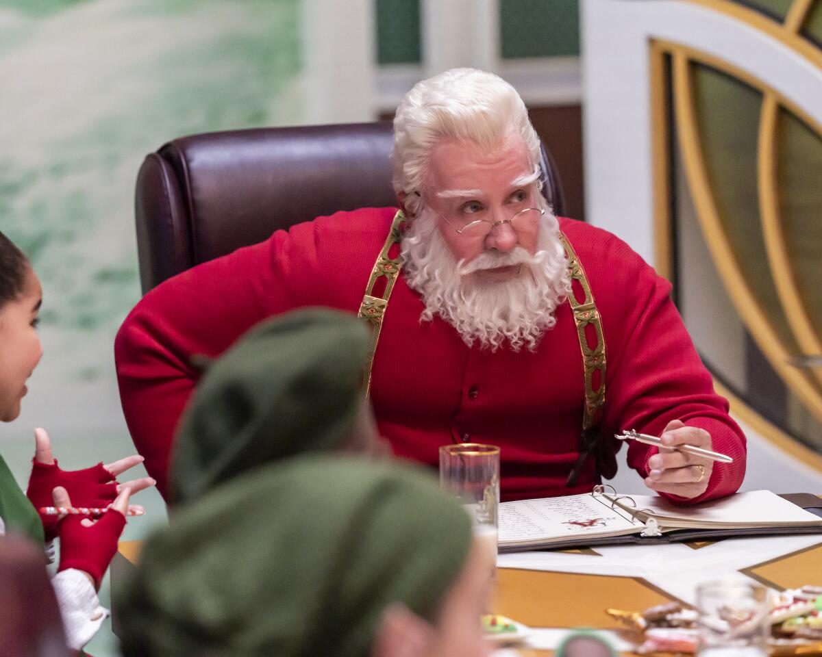 A man dressed as Santa Claus holds a pen while conducting a business meeting.