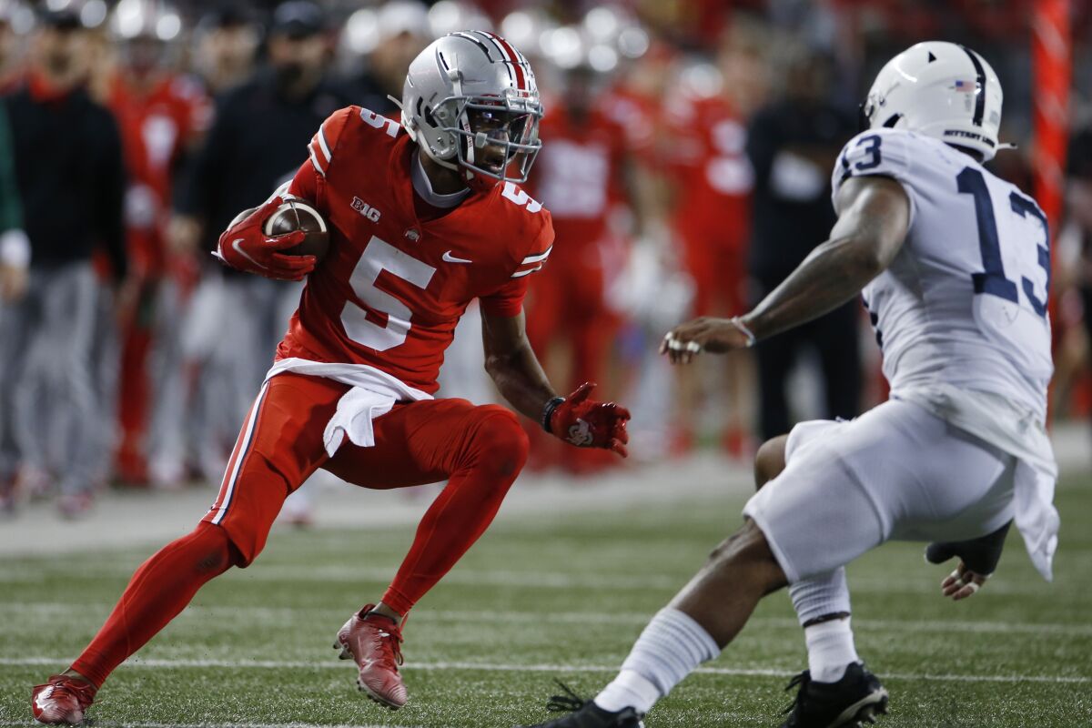 Ohio State receiver Garrett Wilson, left, runs after catching a pass against Penn State linebacker Ellis Brooks during the first half of an NCAA college football game Saturday, Oct. 30, 2021, in Columbus, Ohio. (AP Photo/Jay LaPrete)