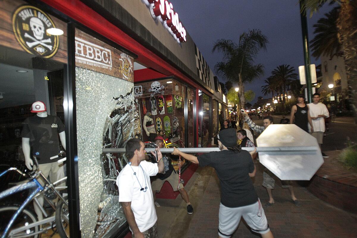 A vandal smashes the window of a Main Street bike shop with a stop sign after last year's U.S. Open of Surfing in Huntington Beach.