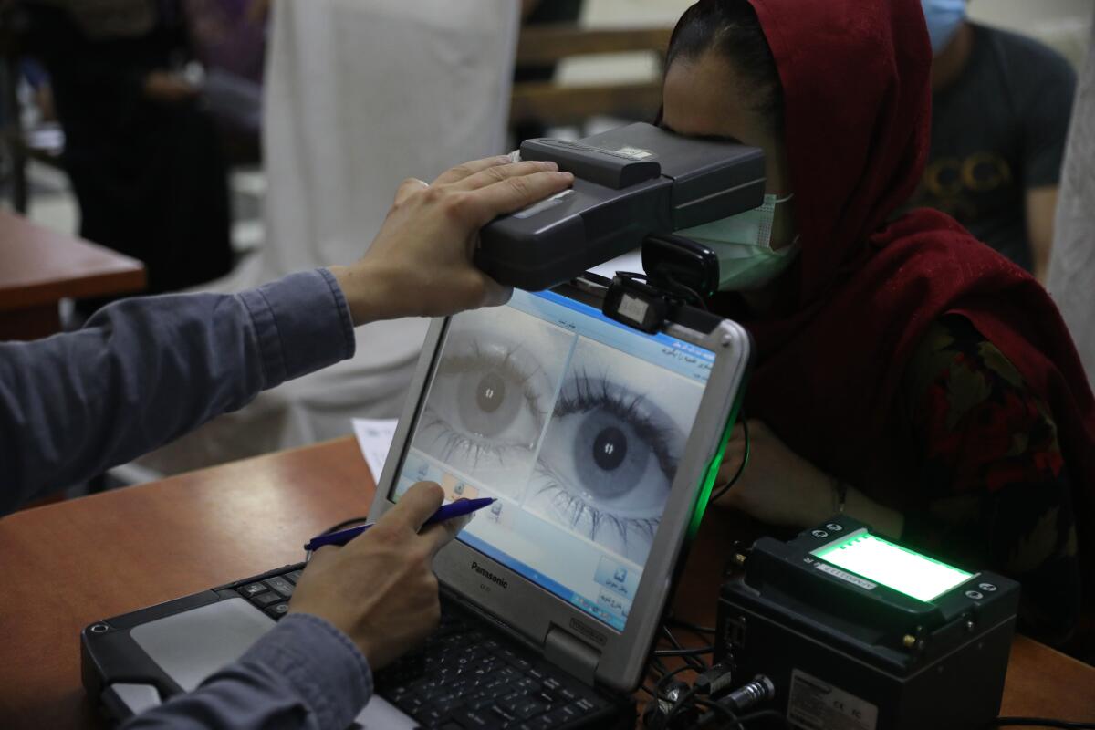 An employee scans the eyes of a woman for biometric data needed to apply for a passport, at the passport office in Kabul, Afghanistan, Wednesday, June 30, 2021. Afghans are lining up by the thousands at the Afghan Passport office to get new passports, possibly to leave, uncertain what tomorrow will bring as they witness the final withdrawal of the U.S. military and its NATO allies. (AP Photo/Rahmat Gul)