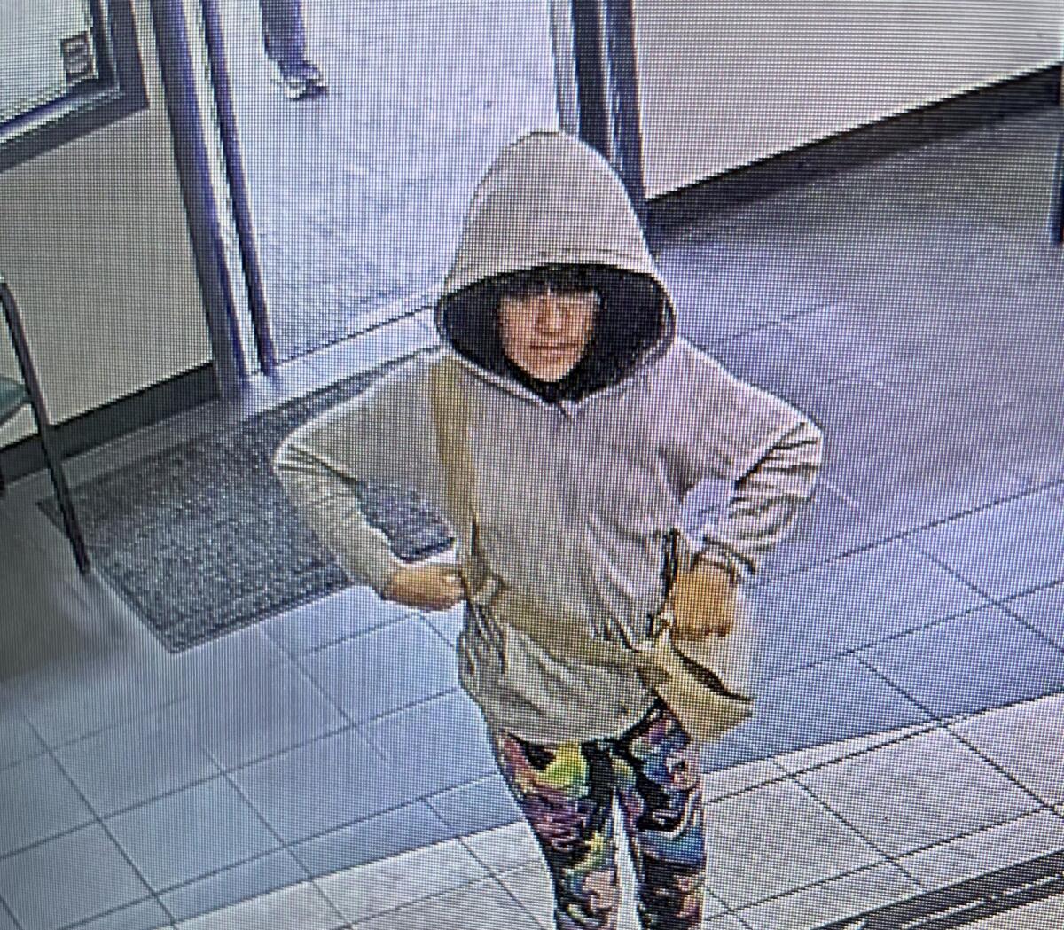 A surveillance image of a person in a hooded jacket.